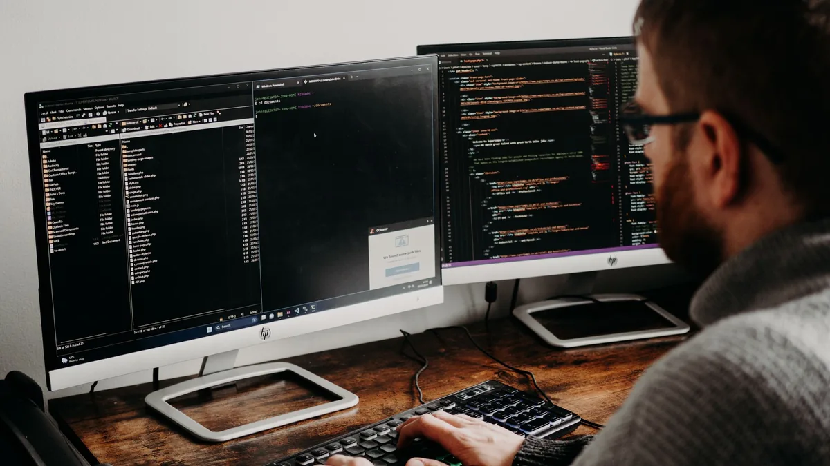 Sviluppatore che analizza dati e codice su due monitor